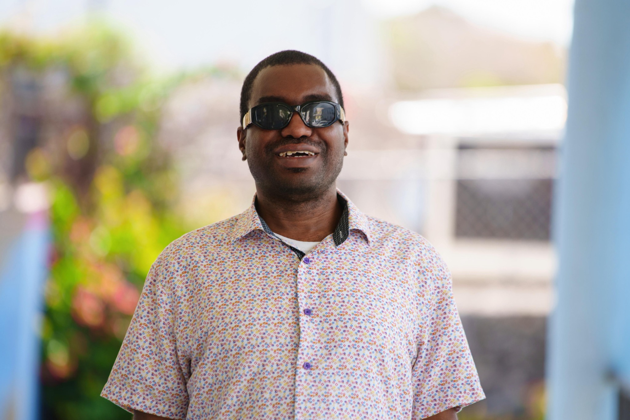 Kevin E. Cartwright standing outdoors and smiling while wearing dark glasses and a patterned shirt.