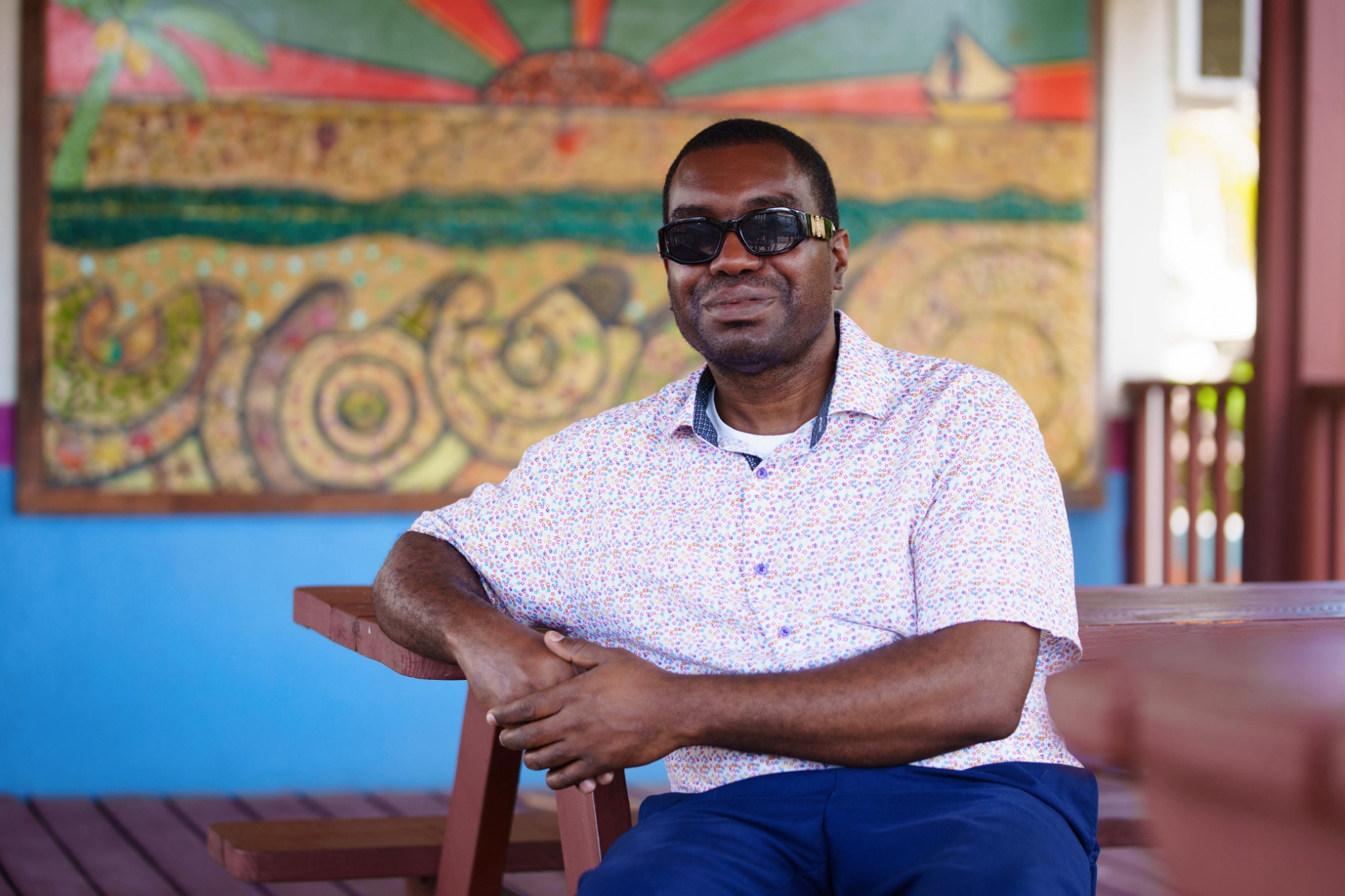 Kevin E. Cartwright in a professional seated pose, wearing dark glasses and a patterned shirt.
